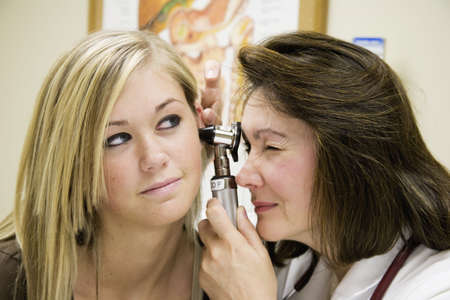 Model Release 307  A doctor examining a teenage female patient with an ear scope.
