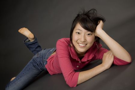 Portrait of a beautiful Asian teenager posing on a gray backgroundの写真素材