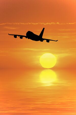 Airliner flying into the sunset over the oceanの写真素材