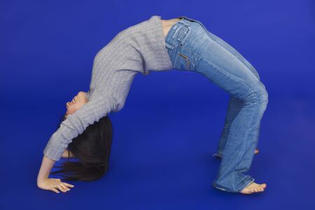 Female Asian teen doing a backbend on a blue background