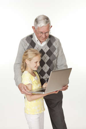 Cute Caucasian granddaughter showing her grandfather something on the computerの写真素材