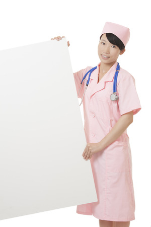 Beautiful Chinese nurse holding a blank sign isolated on a white backgroundの写真素材