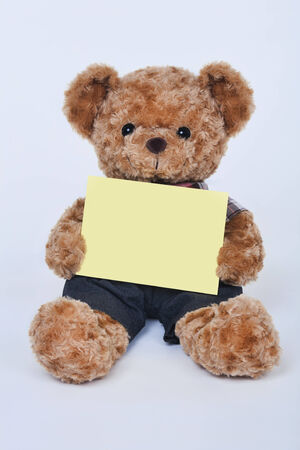 A cute teddy bear holding a blank yellow sign on a white backgroundの写真素材