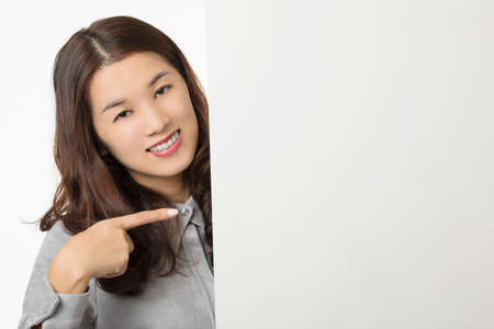 Beautiful Asian woman displaying a bit of attitude while holding a blank card isolated on a white backgroundの写真素材