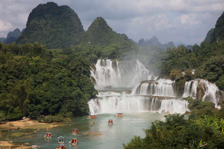 Tourist boats viewing Detian Waterfalls in China, also known as Ban Gioc in Vietnam is the fourth largest transnational waterfalls in the world. Located in Karst hills of Daxin County, Guangxi Province, China and TrÃ¹ng KhÃ¡nh District, Cao Báº±ng Vietnamの写真素材