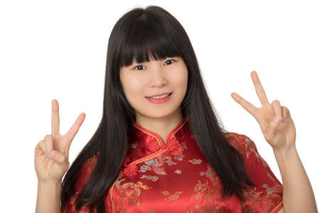 Beautiful Chinese woman wearing a traditional dress known as a Cheongsam or Chipao and giving the...