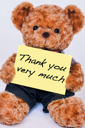Cute teddy bear holding a yellow sign that says Thank you very much isolated on a white backgroundの写真素材