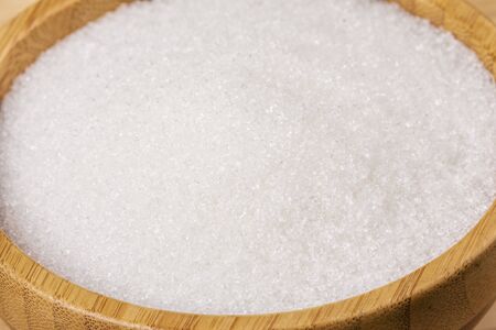 Wooden bowl full of granulated sugar on a wooden backgroundの写真素材