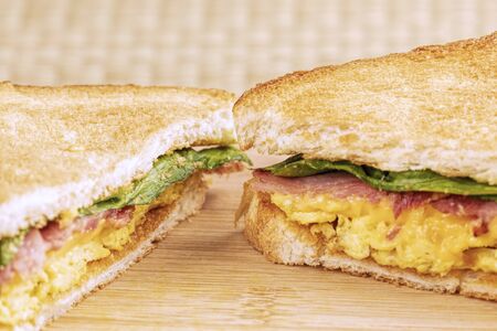 A delicious breakfast sandwich of scrambled eggs and toast with bacon and copy space