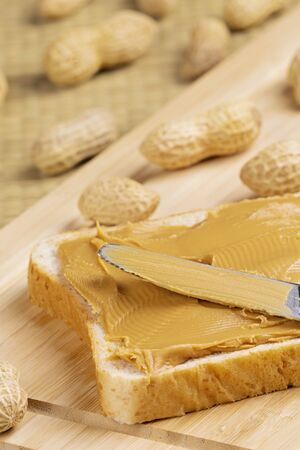 Delicious peanut butter sandwich on a wooden background with peanutsの写真素材