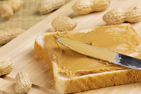 Delicious peanut butter sandwich on a wooden background with peanutsの写真素材