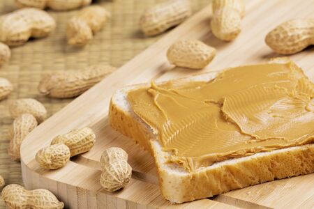 Delicious peanut butter sandwich on a wooden background with peanuts