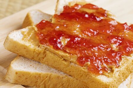 A tasty delicious peanut butter and jam sandwich on a wooden background