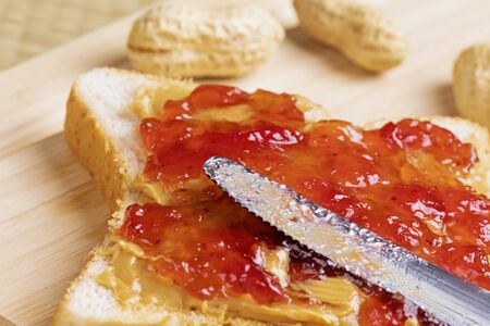 A tasty delicious peanut butter and jam sandwich on a wooden backgroundの写真素材