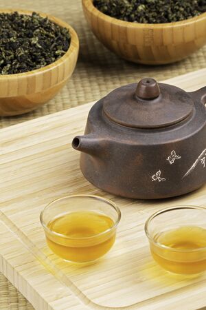 Close up of traditional Chinese tea pot and Green tea isolated on wooden background