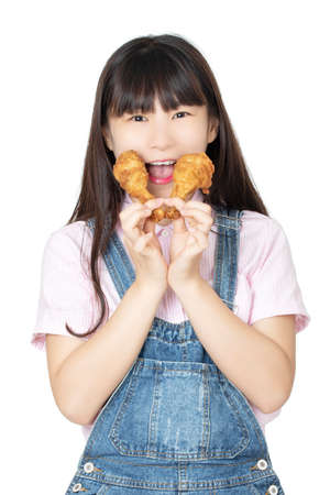 Beautiful Chinese American woman eating a fried chicken drumstick isolated on a white backgroundの写真素材
