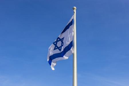 Israel flag flapping in the wind.the flag is flapping and there are blue clouds behind it.の写真素材