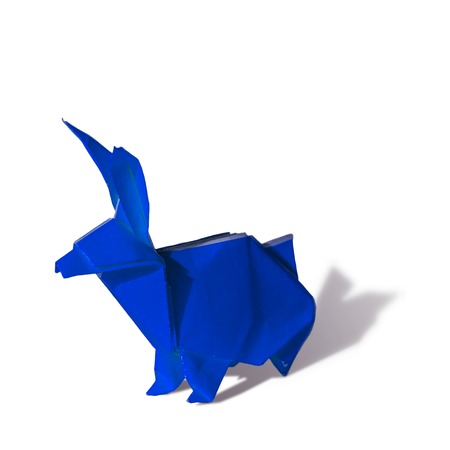 Origami rabbit made of colored paper. the rabbit is standing on a white surface and casts shadow.
It has long pointy ears.の写真素材