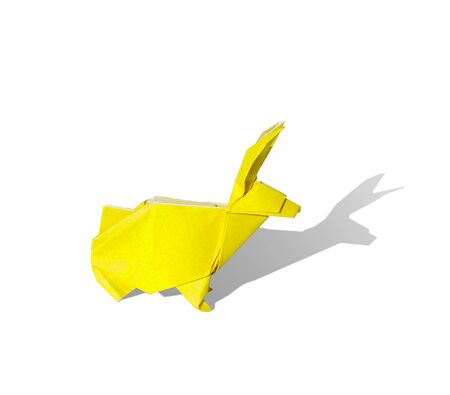 Origami rabbit made of colored paper. the rabbit is standing on a white surface and casts shadow.It has long pointy ears.の写真素材