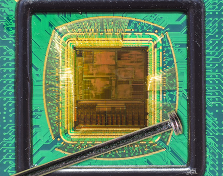 Open computer chip with gold wire connections compared to a needleの写真素材