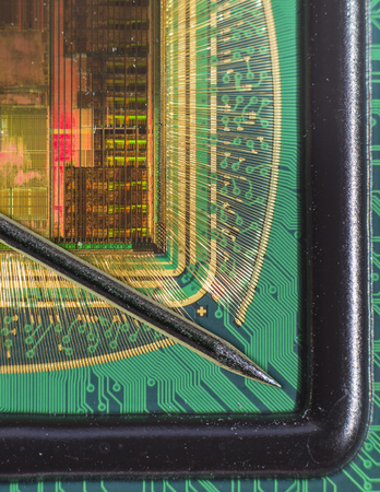 Open computer chip with gold wire connections compared to a needleの写真素材