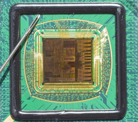 Open computer chip with gold wire connections compared to a needleの写真素材