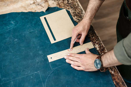 A master sketches for goods from natural leather in his workshop