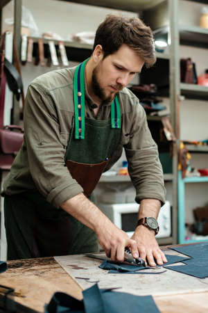 A master cuts natural leather for goods in his workshop