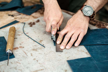 A master cuts natural leather for goods in his workshop