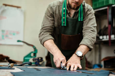 A master cuts natural leather for goods in his workshopの写真素材
