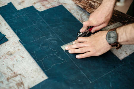 A master cuts natural leather for goods in his workshop