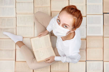 Overhead photo of a student reading a book and wearing a mask. Self-education of a student during...