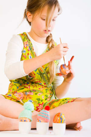 Studio portrait of a young blond girl who is painting easter eggsの写真素材