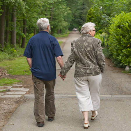 outside portrait of an elderly couple walking along a forest roadの写真素材