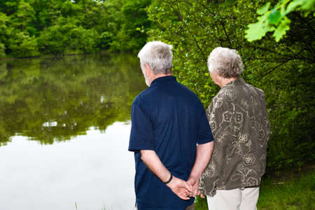 outside portrait of an elderly couple standing near a lakeの写真素材