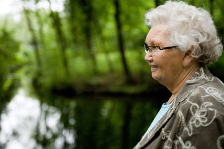 outside portrait of an elderly woman overlooking a streamの写真素材