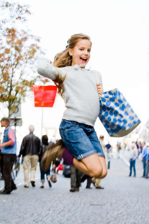 Young cute girl is jumping while shoppingの写真素材