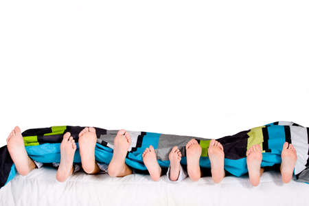 Happy family fun on the bedding isolated on whiteの写真素材