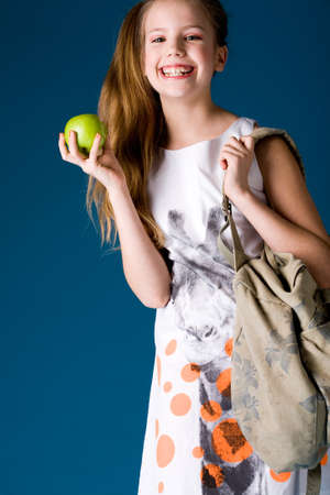 Young cute schoolgirl posing with an appleの写真素材