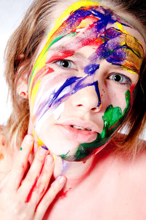 Studio portrait of a teenage girl painting herself