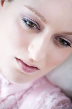 Young blond girl posing in lightpink lingerie nearby a bright window