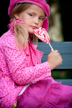 Happy children having pink clothes and a lollipopの写真素材