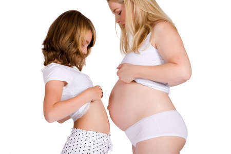 Girl comparing her belly size with the belly of her pregnant aunt.  Made in a studio environment on...