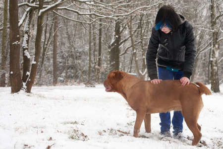 Funky boy is having fun with his dog in the snowの写真素材