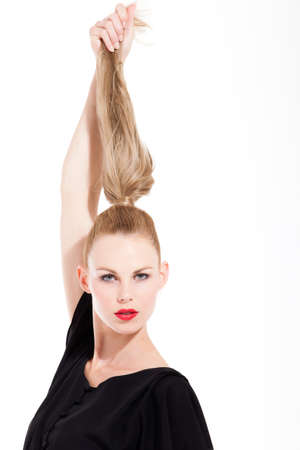 Beautifull young blond woman in the studio holding up her hairの写真素材