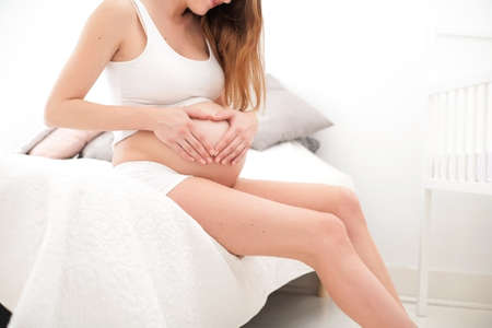 Young new mother is sitting on a bed