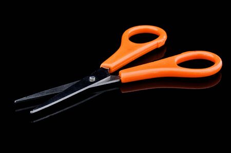 An isolated image of a pair of orange scissors on a black backgroundの写真素材