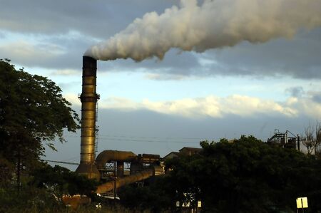 Picture of a smokey sugar mill on a bright sunny dayの写真素材