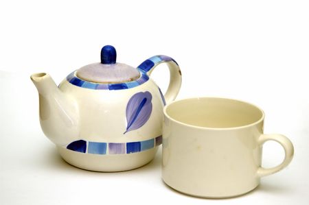 A Ceramic kettle and a tea cup  isolated against a white background
