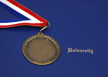 A Certificate and a gold medal on a blue pad - concept of graduationの写真素材